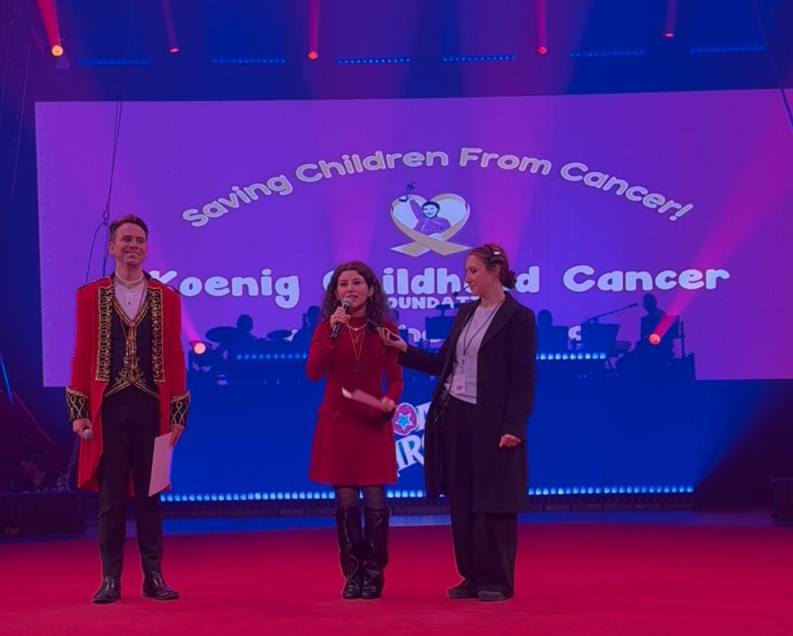 Elana Koenig speaking on stage in front of the KCCF banner